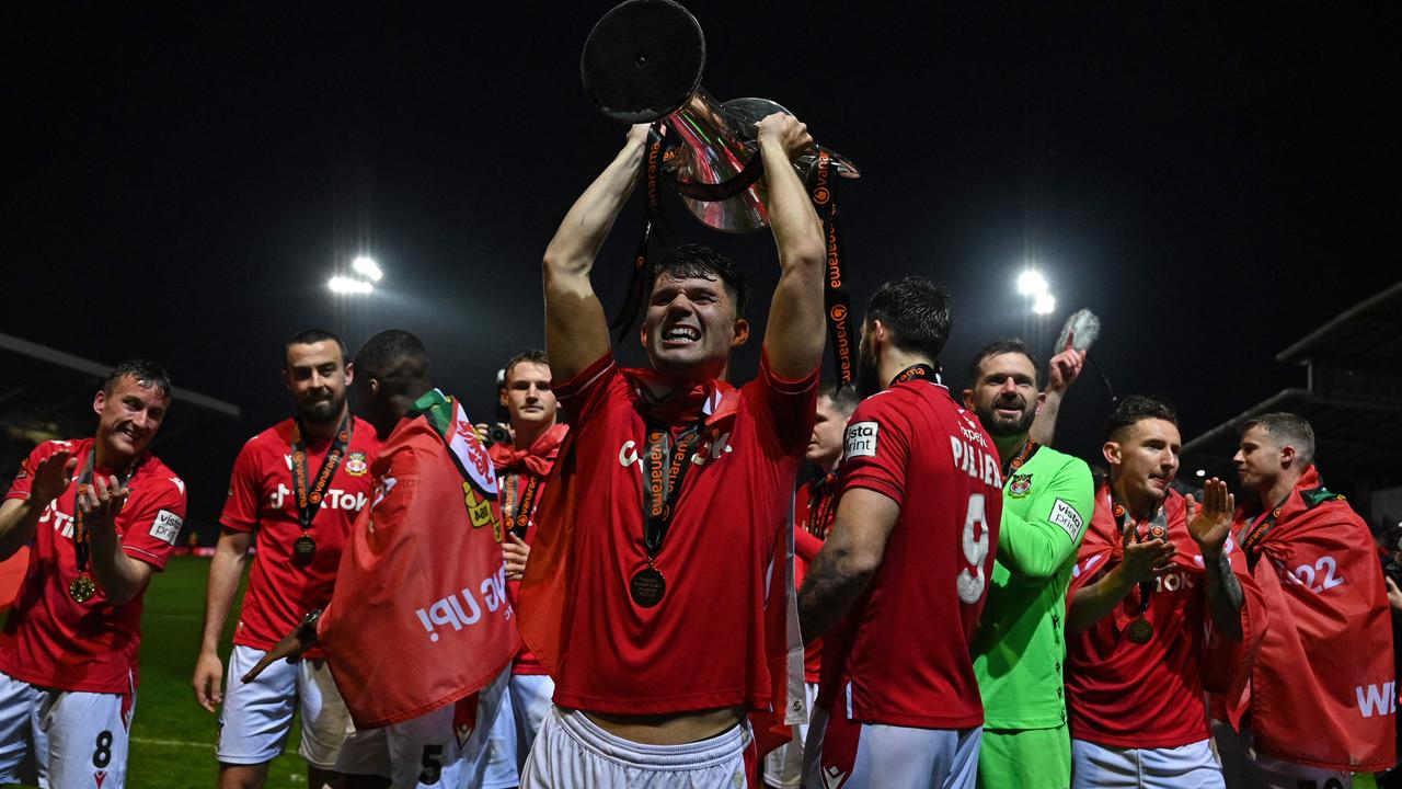 Wrexham's Welsh defender Jordan Davies (C) holds the trophy.