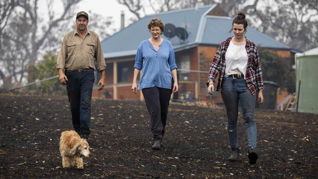 The Schaefers with the family dog, Casey, on their scorched property. Picture: Sean Davey.