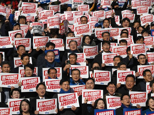 Lawmakers and South Korea's main opposition Democratic Party members hold placards reading "Yoon Suk Yeol should resign!" during a rally against President Yoon Suk Yeol at the National Assembly in Seoul on December 4, 2024, after martial law was lifted in South Korea. Yoon faced demands to resign on December 4 after his short-lived attempt to impose martial law was voted down by lawmakers and brought thousands of protesters to the streets. (Photo by Jung Yeon-je / AFP)