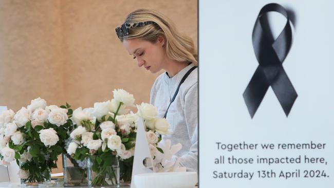 A shopper inspects the thousands of floral tributes left at Bondi Junction shopping centre after it was reopened for business on Friday. Picture: Getty Images