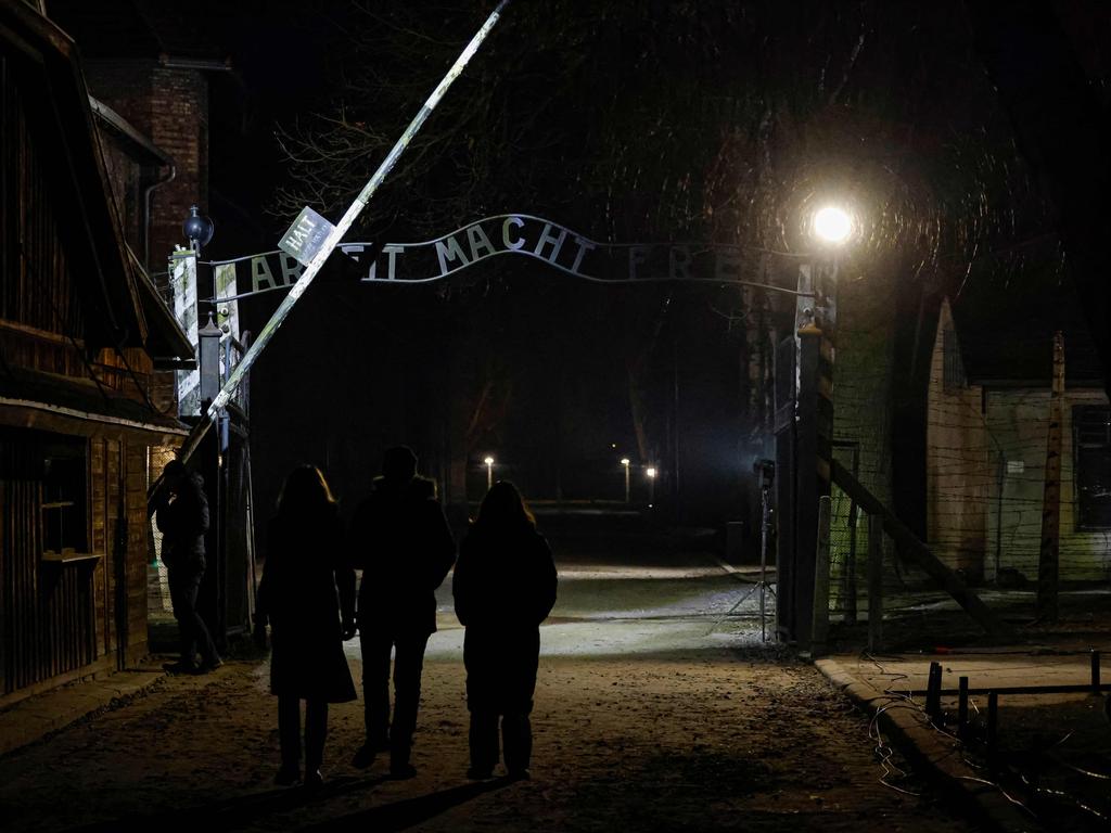 People pass under the gate with the German words "Arbeit Macht Frei" (work will set you free) following the sombre commemorative service at Auschwitz. Picture: Ludovic Marin/ AFP