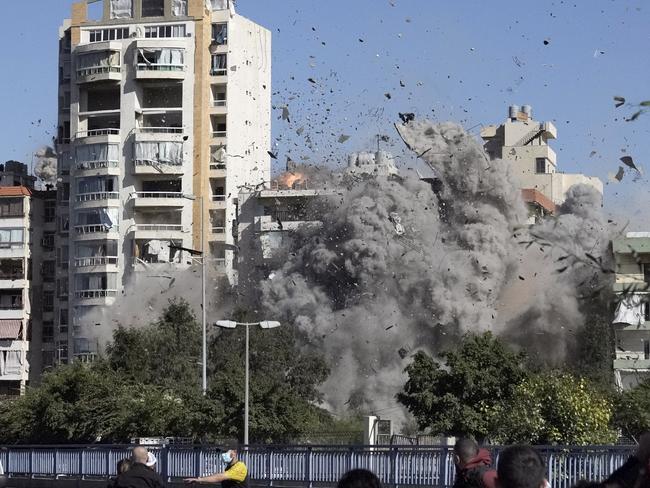 People watch a building collapse after being hit by an Israeli airstrike in Ghobeiri, Beirut, Lebanon, Tuesday, Oct. 22, 2024. (AP Photo/Bilal Hussein)