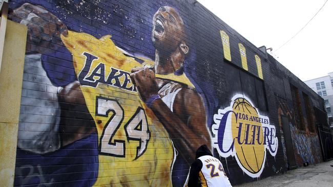 A fan pays respects at a mural depicting Kobe Bryant in a downtown Los Angeles alley. Picture: AP