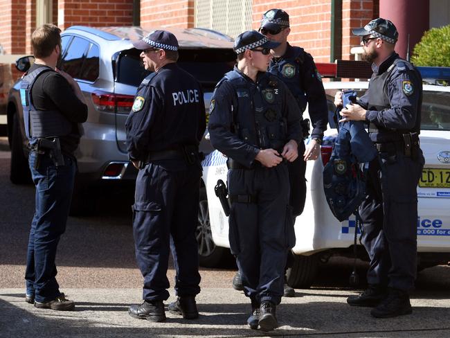 Police come out of a flat in Lakemba they have just raided. Picture: AFP/William West