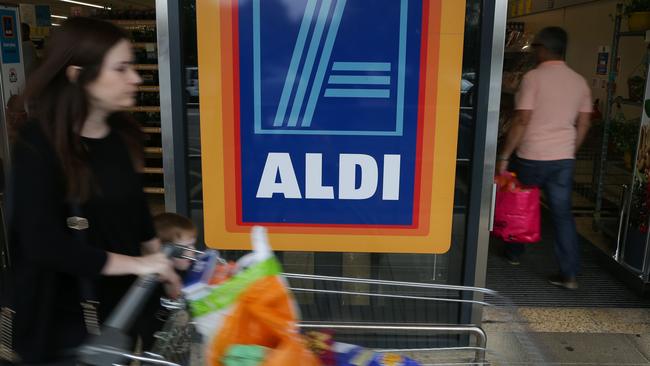 A woman pushes a shoping trolley past an Aldi logo as she leaves one of the company's supermarket stores in London on September 26, 2016. Aldi UK announced on Monday that it will invest £300 million ($389 million, 346 million euros) to revamp its stores over the next three years. Aldi and its German rival Lidl have boomed in Britain, grabbing market share from traditional supermarkets Asda, Morrison, Sainsbury's and Tesco, as customers tightened their belts to save cash. / AFP PHOTO / Daniel Leal-Olivas