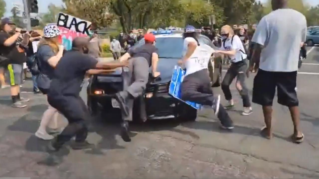 Police car drives through anti-Trump protesters in California.