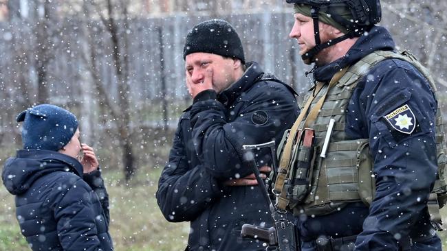 People react as they gather close to a mass grave in the town of BuchaSergei Supinsky/AFP