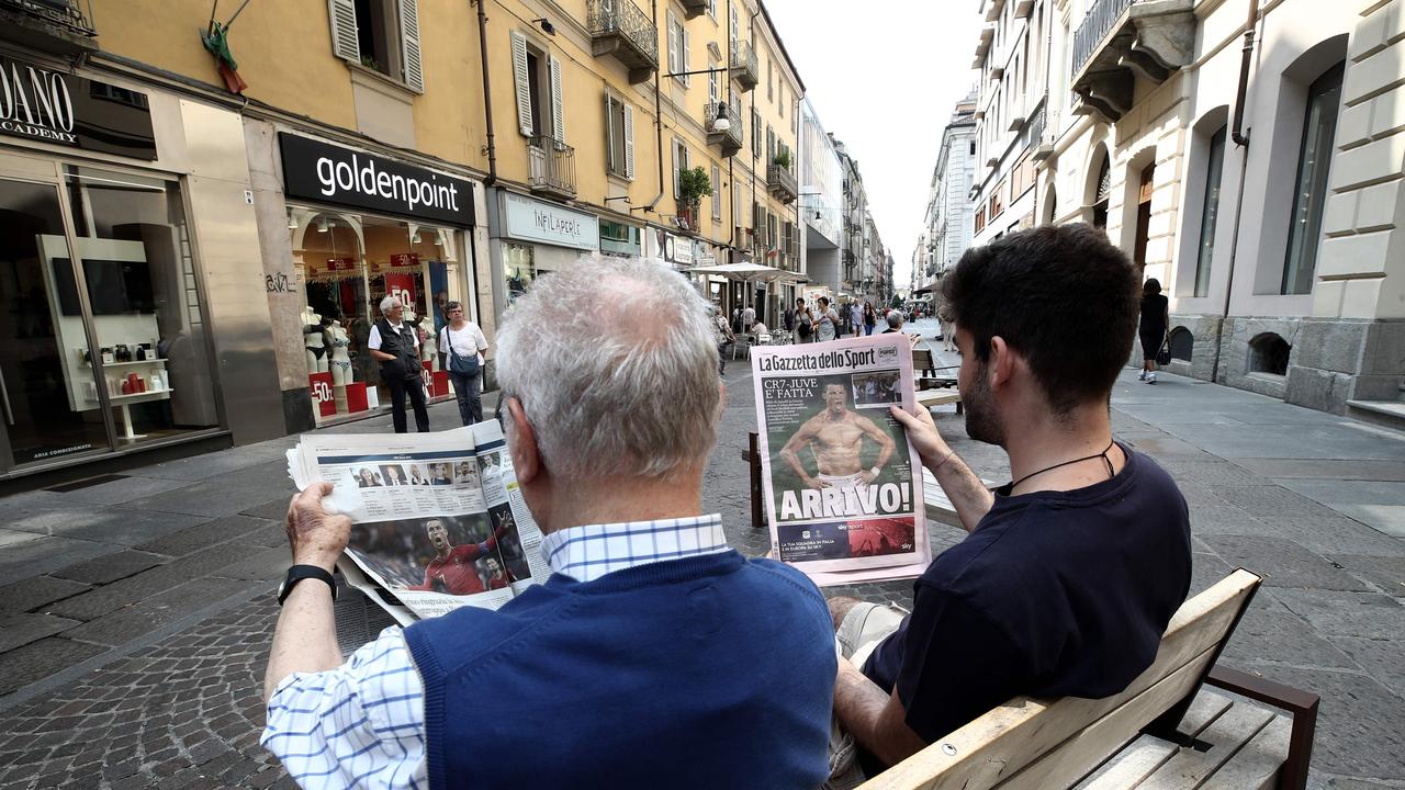 Two men in via Lagrange downtown Turin read news on Italian newspapers about Cristiano Ronaldo's arrival in downtown Turin