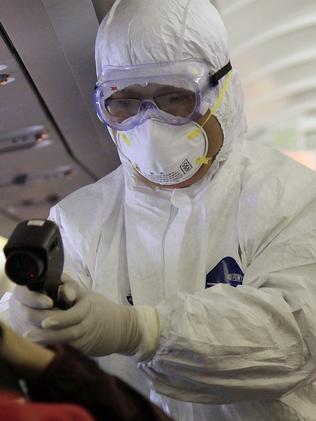 A Chinese health inspector in protective outfits checks the body temperature of a passenger on an aeroplane in China in 2009.