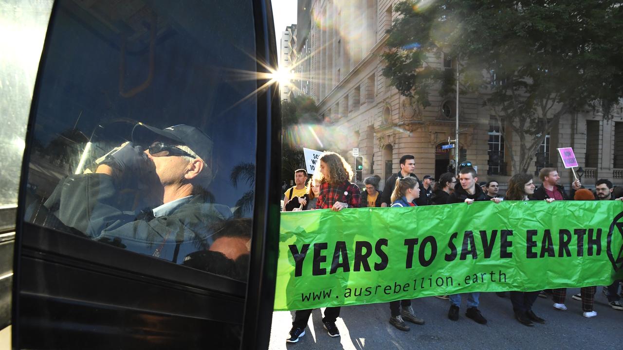 A bus driver seen in the reflection of his mirror waits as Extinction Rebellion protesters block early morning peak hour traffic in Brisbane, Thursday, July 11, 2019. Picture: Dave Hunt/AAP