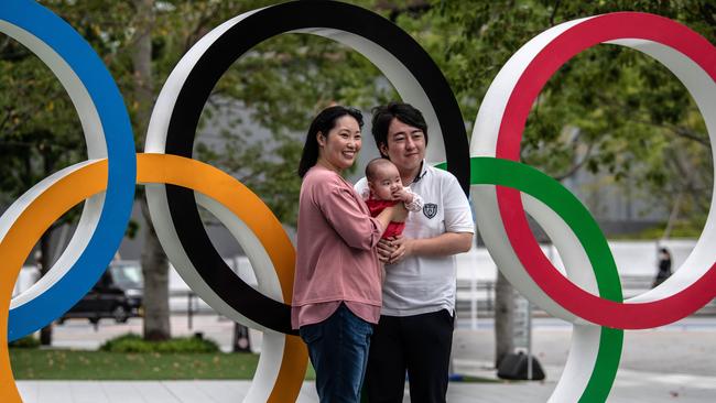 A couple hold their baby for a photograph next to the Olympic Rings in Tokyo, Japan. Picture: Getty Images