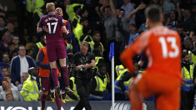 Chelsea's Belgian goalkeeper Thibaut Courtois (R) looks on as Manchester City's Belgian midfielder Kevin De Bruyne celebrates with teammates after scoring.