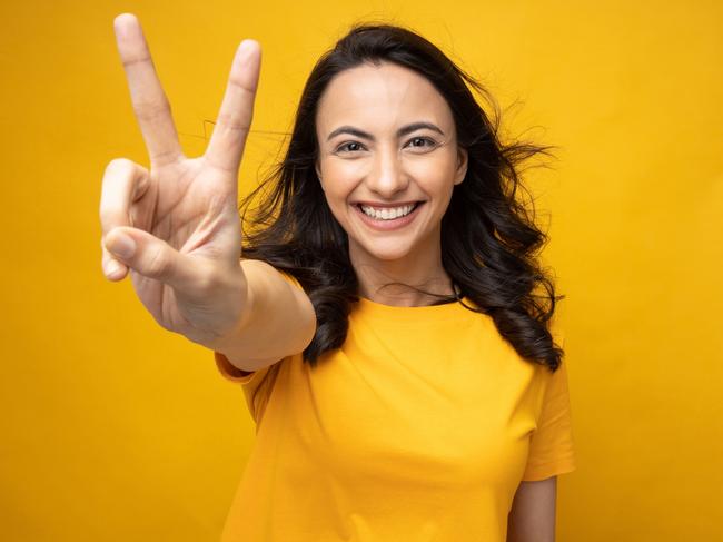 Portrait of young woman wear trendy smart casual outfit isolated on yellow background; two fingers double-digit victory sign generic