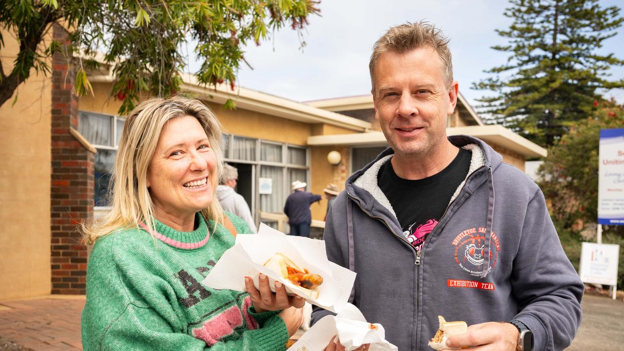 Kylie Darmody, 50, and Sean Tierney, 50 from Kingston Park hold up sausages at Seacliff Uniting Church polling place. Picture: NCA NewsWire / Morgan Sette