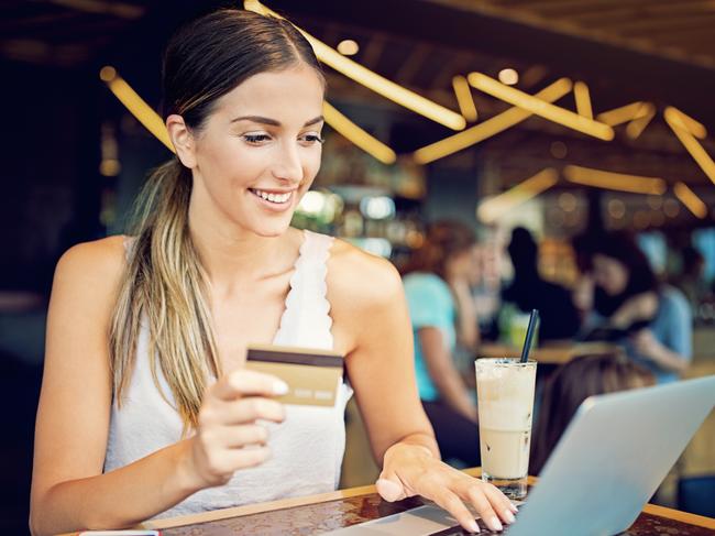 Young girl is shopping online in the cafe using laptop and her credit card