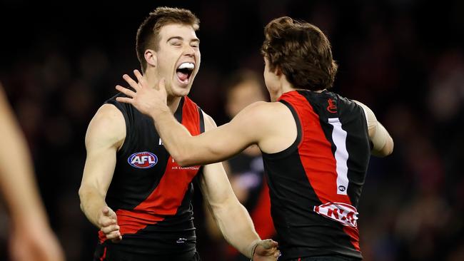 Zach Merrett of the Bombers (left) celebrates a goal with Andrew McGrath.