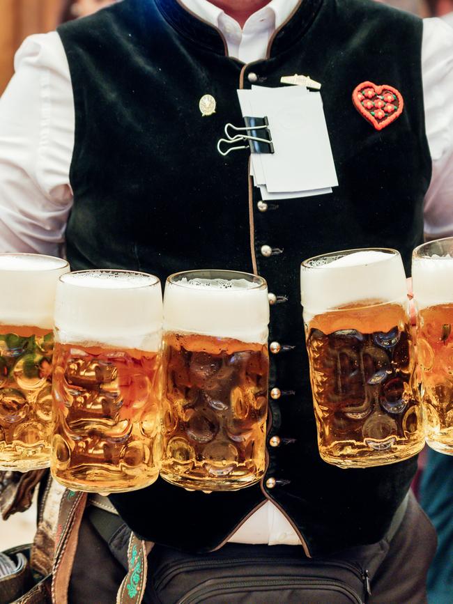 A waiter carrying a lot of beer glasses in beer garden at Octoberfest in Munich