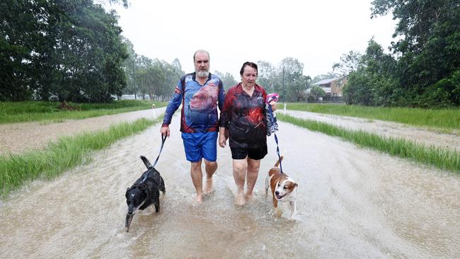 Cardwell residents David and Tracy Ebert walk their dogs down Gregory Street, after flood water inundated their home. Picture: Brendan Radke