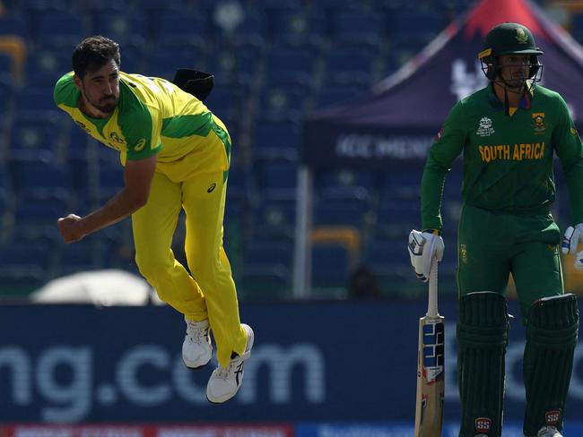 Australia's Mitchell Starc (L) bowls as South Africa's Quinton de Kock watches during the ICC menâs Twenty20 World Cup cricket match between Australia and South Africa at the Sheikh Zayed Cricket Stadium in Abu Dhabi on October 23, 2021. (Photo by INDRANIL MUKHERJEE / AFP)