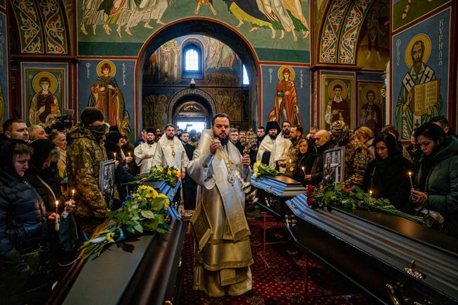 Mourners, many in camouflage and covering their faces, attend a service in a Kyiv church for four men killed during a December incursion into Russia's southern Bryansk region