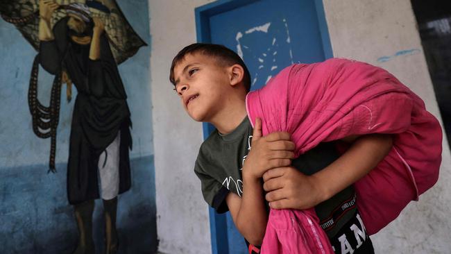 A Palestinian boy carries his belongings in a school where he was taking shelter with his family as as they return to their house in Gaza City. Picture: AFP