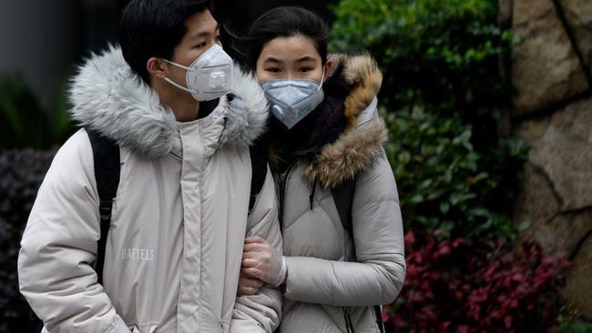 A couple wearing protective facemasks walks along a street in Shanghai. Picture: AFP