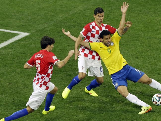 Brazil's Fred, right, falls after making contact with Croatia's Dejan Lovren during the group A World Cup soccer match between Brazil and Croatia, the opening game of the tournament, in the Itaquerao Stadium in Sao Paulo, Brazil, Thursday, June 12, 2014. At left is Croatia's Vedran Corluka. (AP Photo/Thanassis Stavrakis)