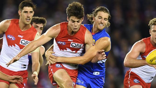 George Hewett gets his kick away while being tackled by Marcus Bontempelli.