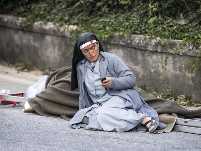 An image of a nun checking her mobile has become one of the defining images of the Italian quake. Picture: Massimo Percossi/ANSA via AP.