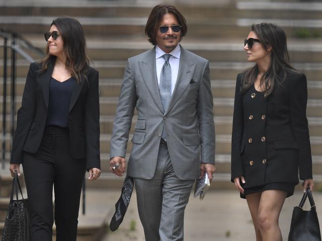 Johnny Depp, centre, flashing a smirk with members of his team after day eight of his libel trial. Picture: AFP