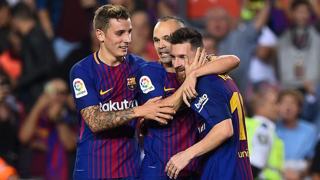 Barcelona's midfielder Andres Iniesta (C) is congratulated by his teammates Lucas Digne (L) and Lionel Messi.