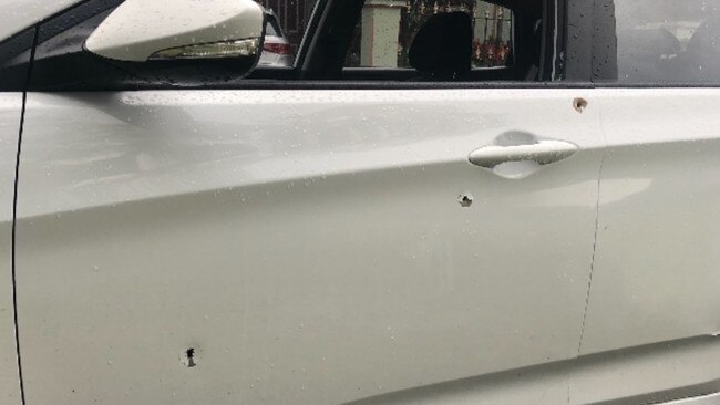 The damaged white Hyundai Accent hatchback with bullet holes.