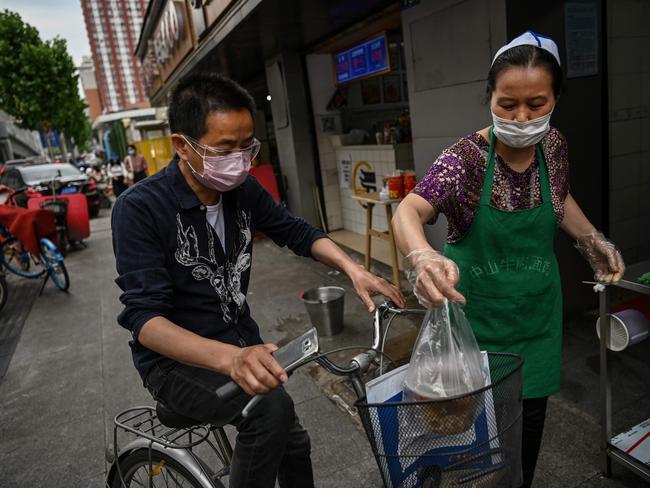 A man wearing a face mask and goggles buys food from a small restaurant in Wuhan. Picture: AFP