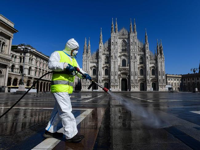 An employee wearing protective gear, working for environmental services company AMSA, sprays disinfectant on Piazza Duomo in Milan. Picture: AFP