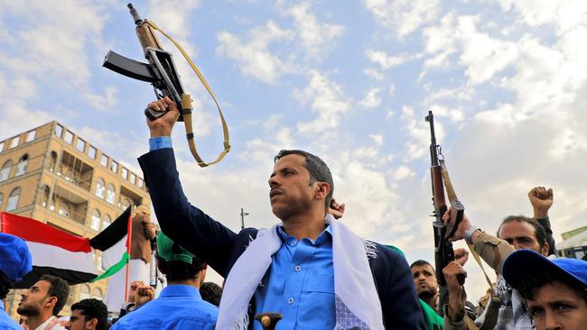 Yemenis brandish rifles and wave Palestinian flags during a march in solidarity with the people of Gaza.