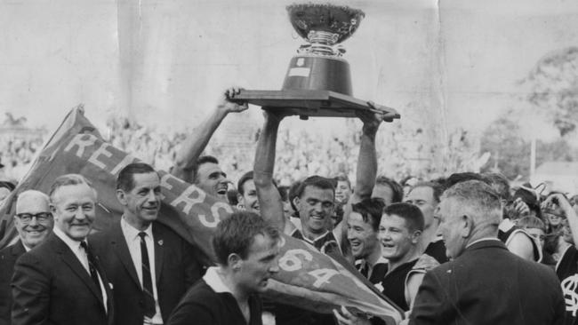 Neil Kerley holds aloft the Thomas Seymour Hill premiership cup after taking South Adelaide from bottom to top in 1964.