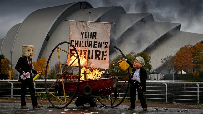 Activists from Ocean Rebellion dressed as Boris Johnson and an Oilhead set light to the sail of a small boat as they protest next to the River Clyde opposite the COP26 site on October 27 in Glasgow.