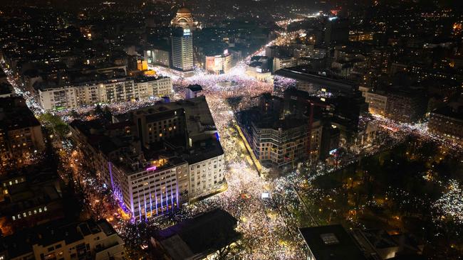 Protesters holding up their mobile phones to light up the night sky. Picture: Djordje Kostic/AFP