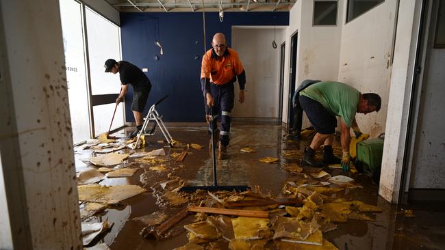 People clean debris from a flood-damaged business in Lismore, Australia.