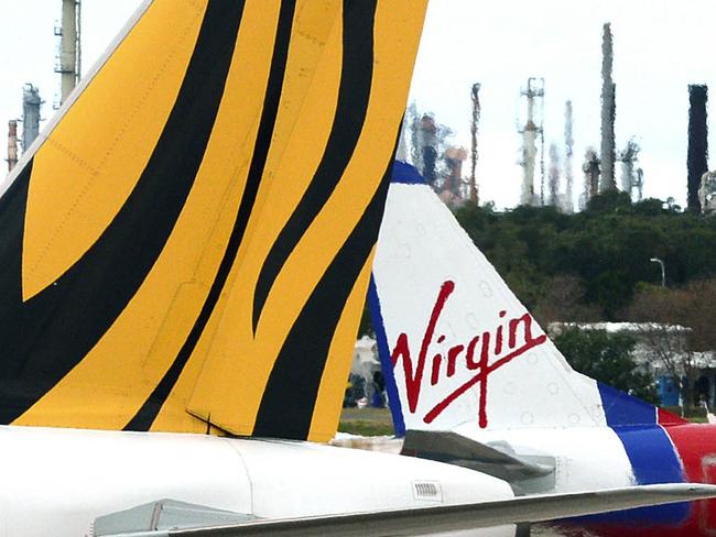 A Virgin Australia plane passes by a Tiger Airways passenger jet at Brisbane airport, Tuesday, Oct. 30, 2012. Virgin Australia is to expand its presence in Australia and Asia after buying a major stake in Tiger Airways. (AAP Image/Dan Peled) NO ARCHIVING