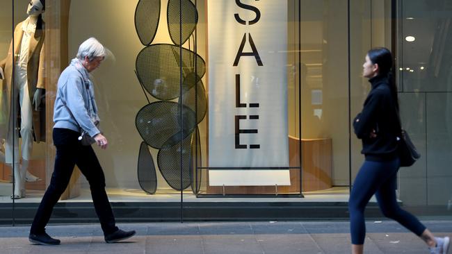 Shoppers walk past retail signage in Sydney. Picture: AAP