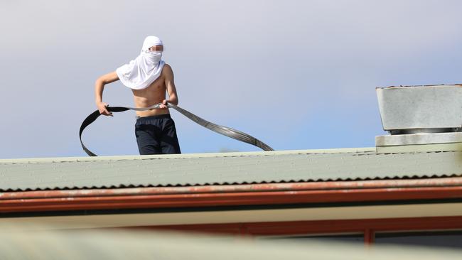 A youth with a fire hose on the roof of Parkville Juvenile Justice Centre. Picture: Alex Coppel