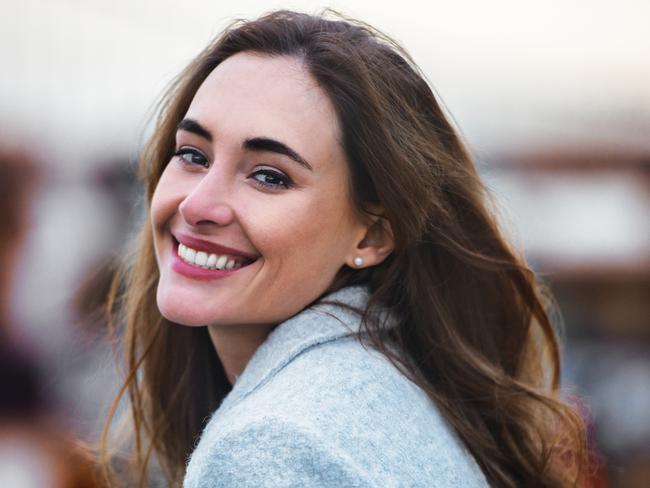 Close-up portrait of beautiful caucasian woman with charming smile walking outdoors