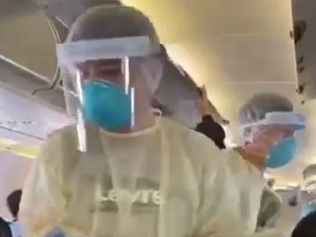 People on a domestic flight out of the central Chinese city of Wuhan having their temperature taken one-by-one by people in protective suits. Picture: Twitter