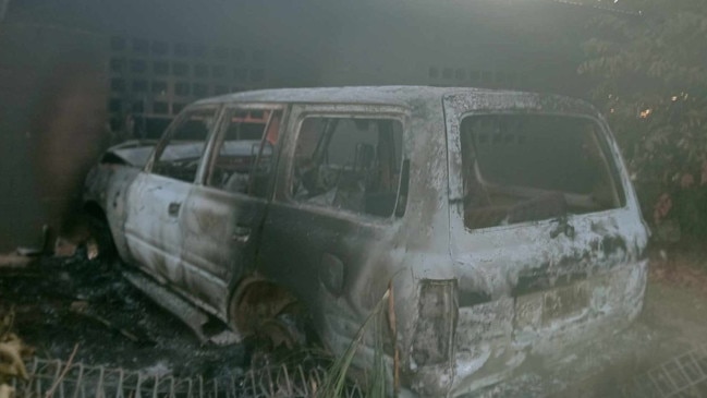 A torched car can be seen smashed into a building.