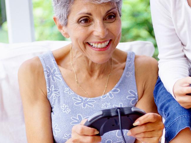 View of a girl (8-10) playing a video game with her grandmother. Generic image.