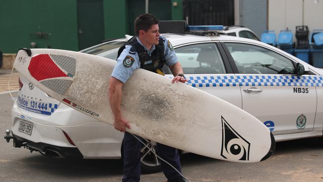 A police officer with the man’s surfboard. Picture John Grainger