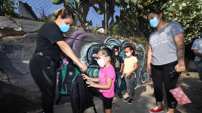 A volunteer hands three-year-old Zayla a backpack filled with school supplies at a distribution to support neighbourhood families in Los Angeles, California, as part of a COVID-19 community rescue program.