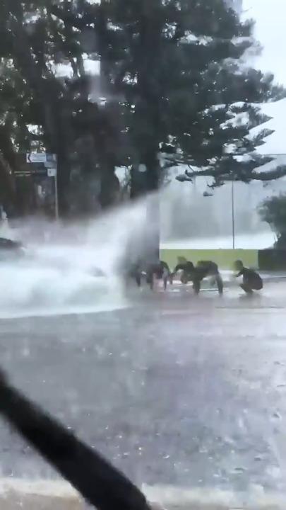 Surfers make the most of Sydney storm by asking cars for a "wave" splash