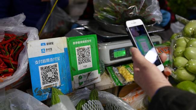 A customer makes a payment using a Wechat QR payment code via her smartphone, next to an Alipay QR code. Picture: AFP